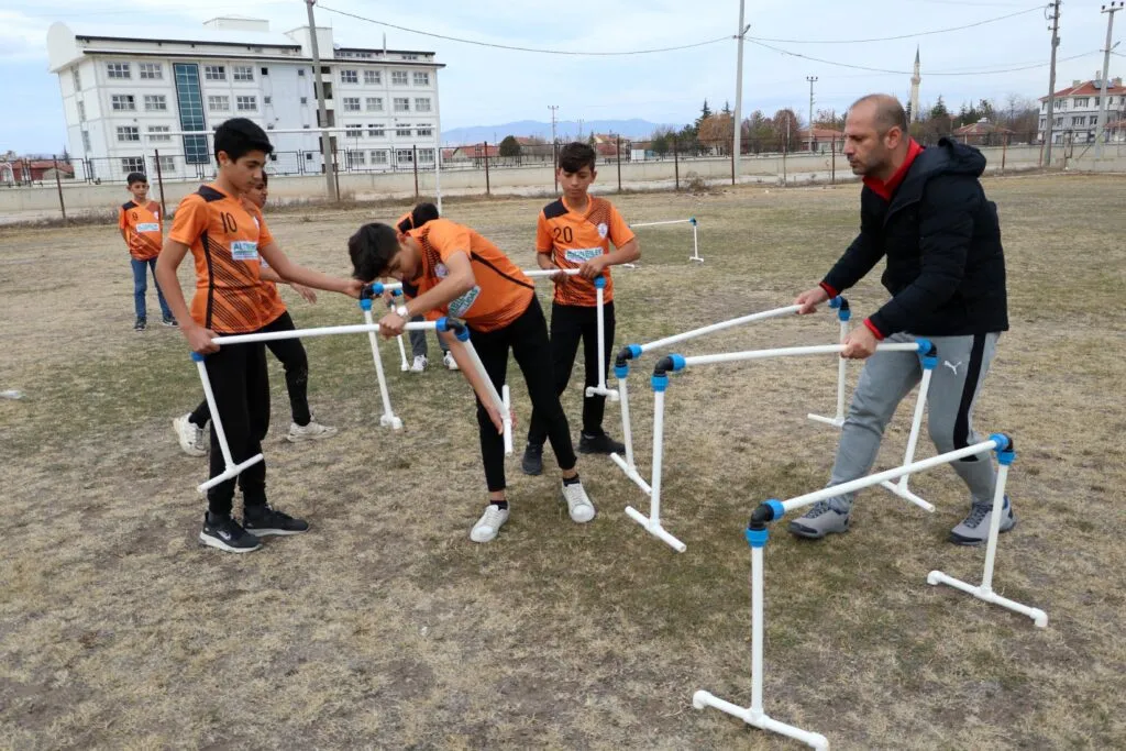 Öğrencilerini, su borularından yaptığı engelli parkuruyla yarışlara hazırlıyor